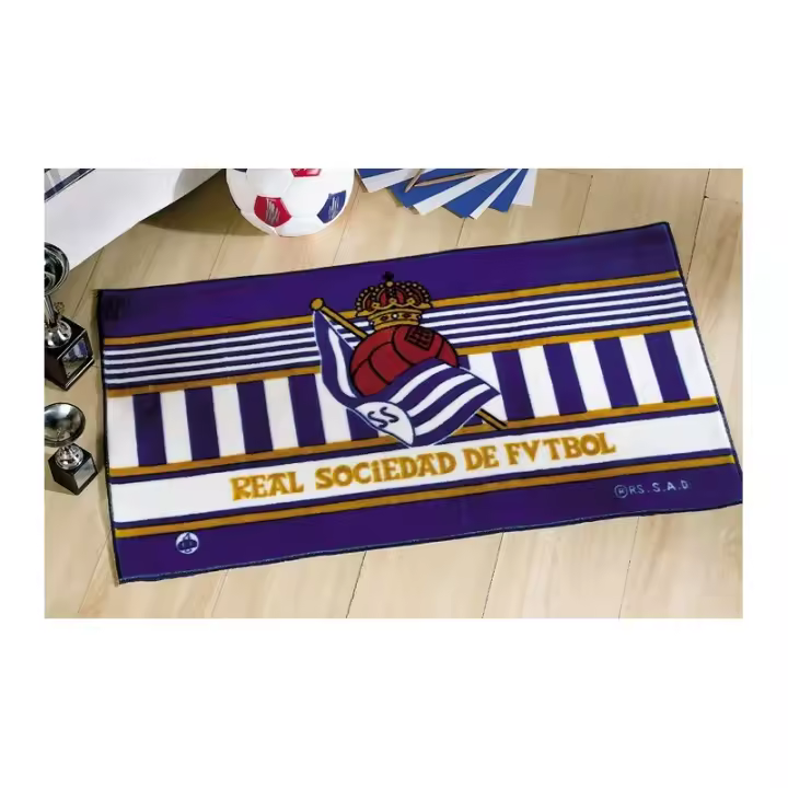 Alfombra Tapete Real Sociedad de Futbol.  Ideal para colocar a los pies de la cama.  Medidas: 55x110 cm.  Composición: 85% acrílico 15% poliéster  Los colores pueden diferir ligeramente de la imagen mostrada  Fabricado en España  Licencia Oficial - 1