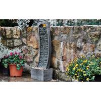 Outdoor water fountain is shown with plants in a stone courtyard