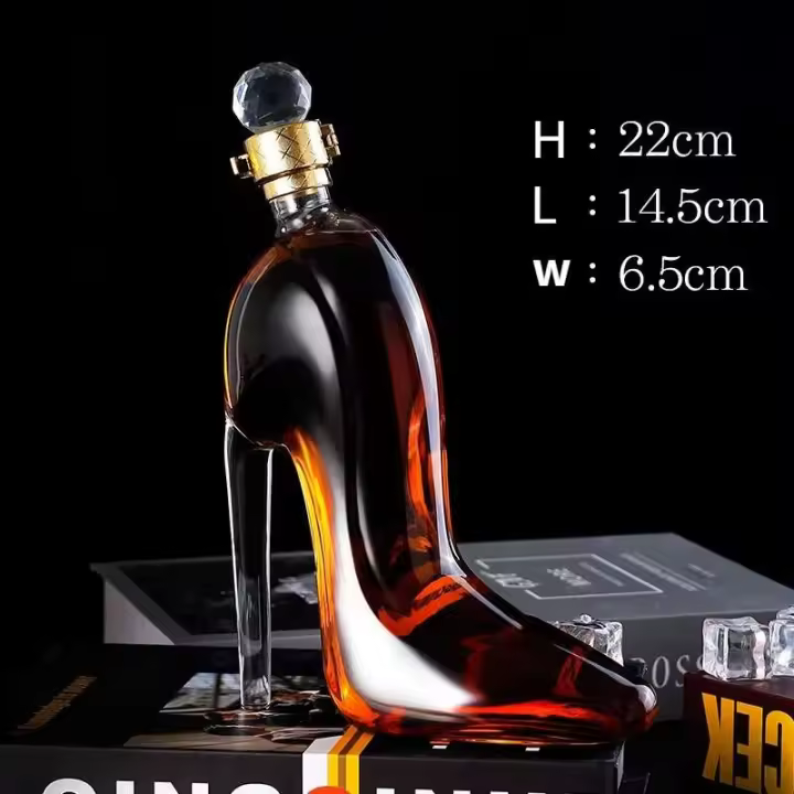 Un diseño innovador de zapato de tacón alto de vino tinto, un vaso vacío con tapa sellada y una botella de whisky gruesa. - 1