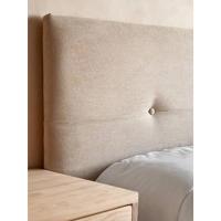Ambiente de dormitorio con un primer plano de un cabecero tapizado en beige