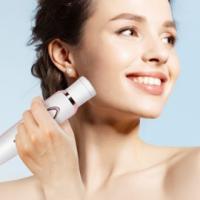 a woman who is shaving her face with a shaver
